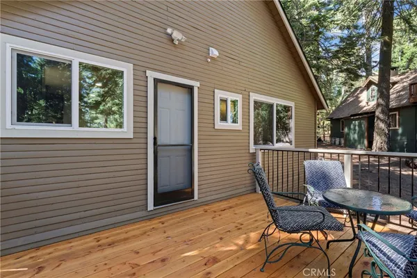 a view of a patio with table and chairs with wooden floor and fence