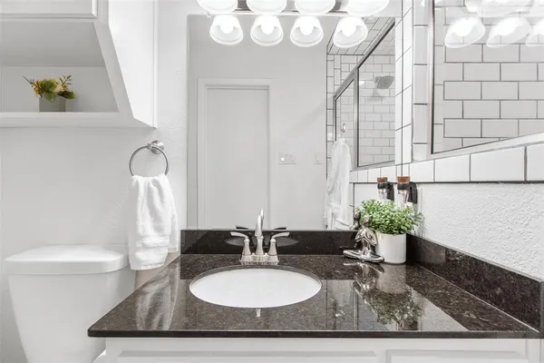 a bathroom with a granite countertop sink a toilet and mirror