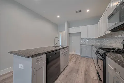 a kitchen with granite countertop a stove top oven and sink