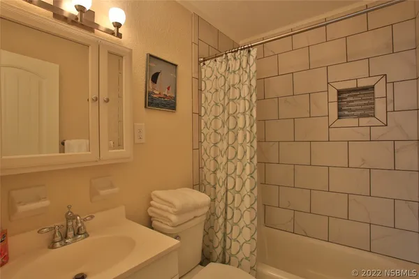 a bathroom with a sink a toilet and shower curtain
