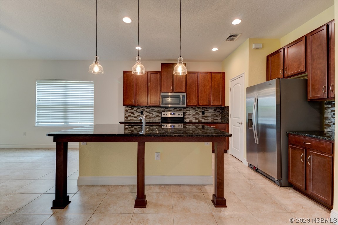 5421 Estero Loop Port Orange, FL 32128 - Photo 6 of 30 a kitchen with stainless steel appliances kitchen island granite countertop a refrigerator a stove and a sink with wooden floor