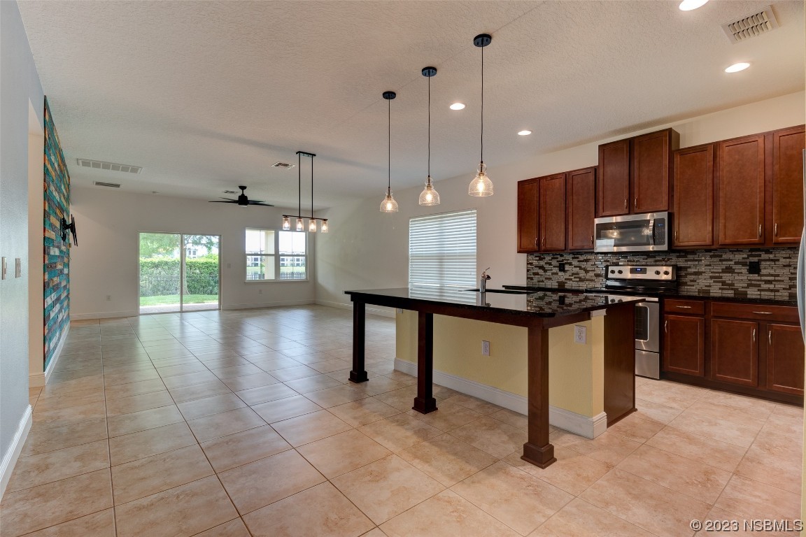 5421 Estero Loop Port Orange, FL 32128 - Photo 8 of 30 a kitchen with stainless steel appliances kitchen island granite countertop a stove a sink and a microwave