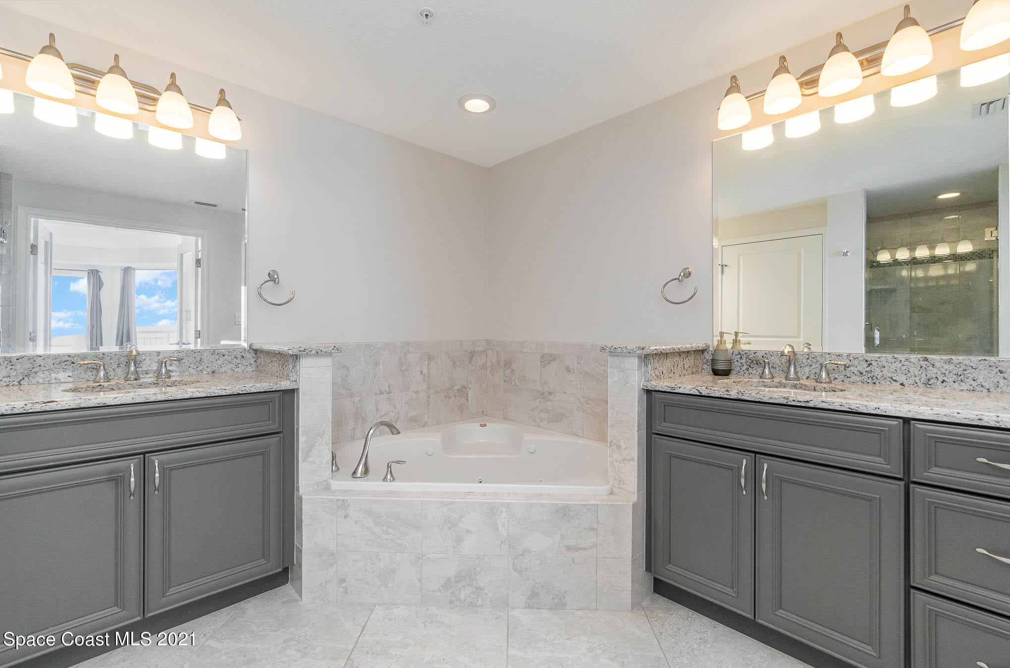 1045 Florida A1A, Unit 503 Satellite Beach, FL 32937 - Photo 13 of 23 a bathroom with a granite countertop bathtub a sink and a mirror