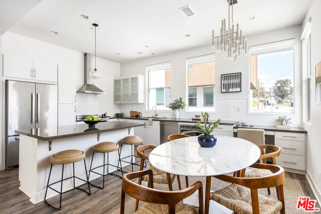 a kitchen with stainless steel appliances a dining table chairs and a chandelier