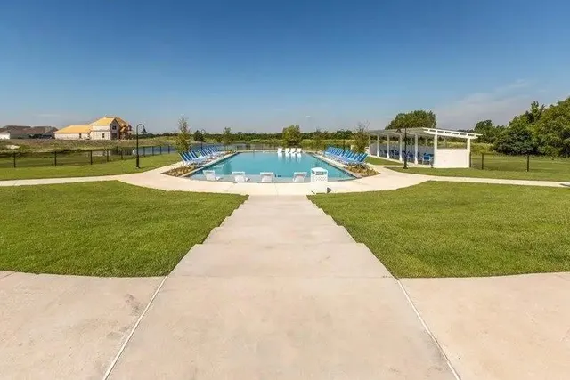 a view of swimming pool with lawn chairs and large trees