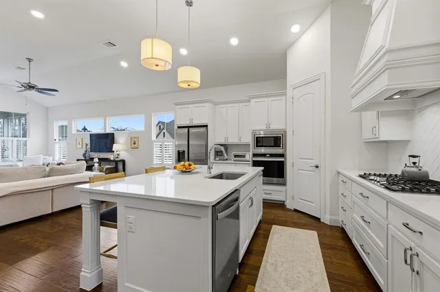 a kitchen that has a lot of cabinets a sink and wooden floor