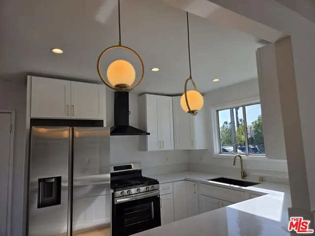 a kitchen with a sink stainless steel appliances a window and cabinets