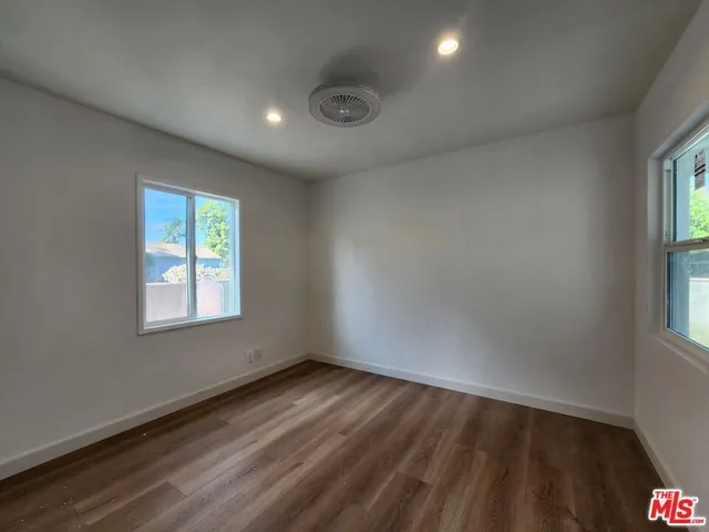 an empty room with wooden floor closet and windows