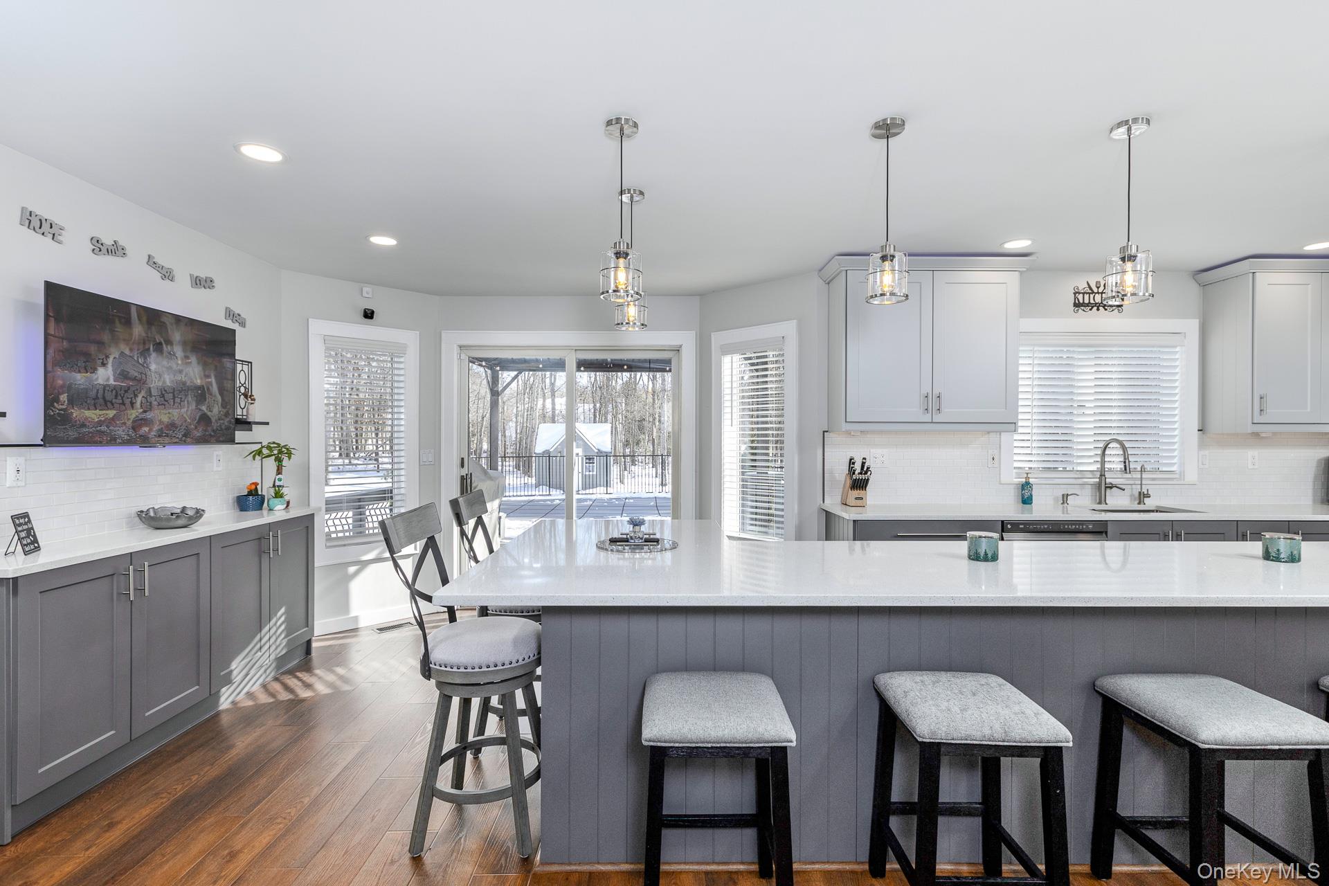 503 Wading River Road Manorville, NY 11949 - Photo 13 of 45 Kitchen featuring gray cabinetry, backsplash, a kitchen bar, dark wood finished floors, and recessed lighting