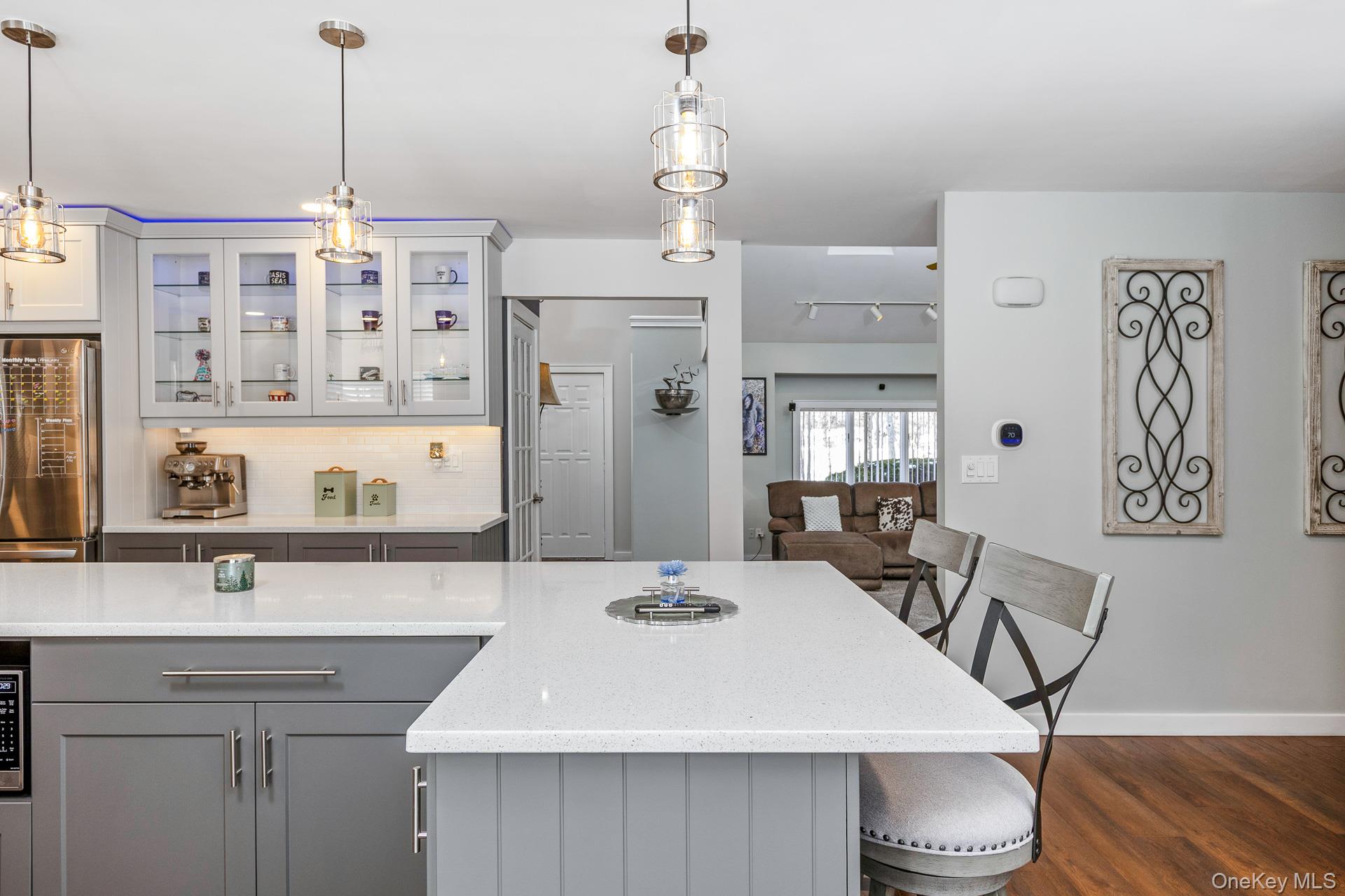 503 Wading River Road Manorville, NY 11949 - Photo 16 of 45 Kitchen featuring gray cabinets, stainless steel refrigerator, light stone countertops, a breakfast bar, and decorative backsplash