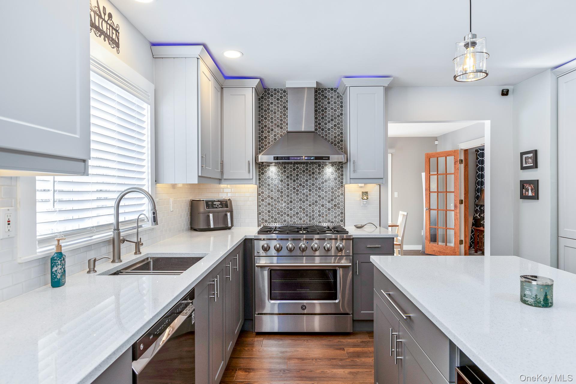 503 Wading River Road Manorville, NY 11949 - Photo 17 of 45 Kitchen featuring stainless steel appliances, gray cabinetry, wall chimney range hood, light stone counters, and hanging light fixtures