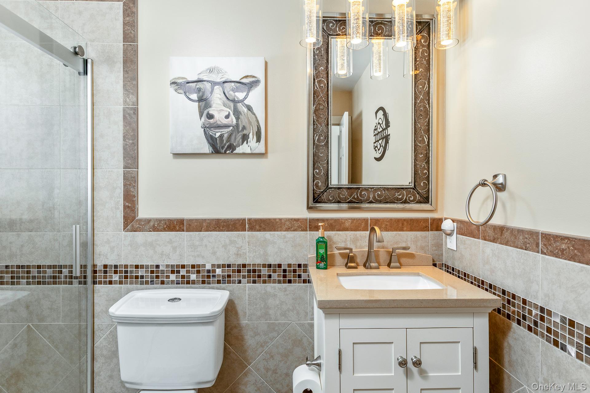 503 Wading River Road Manorville, NY 11949 - Photo 20 of 45 Full bathroom featuring vanity, tiled shower, tile walls, and a wainscoted wall