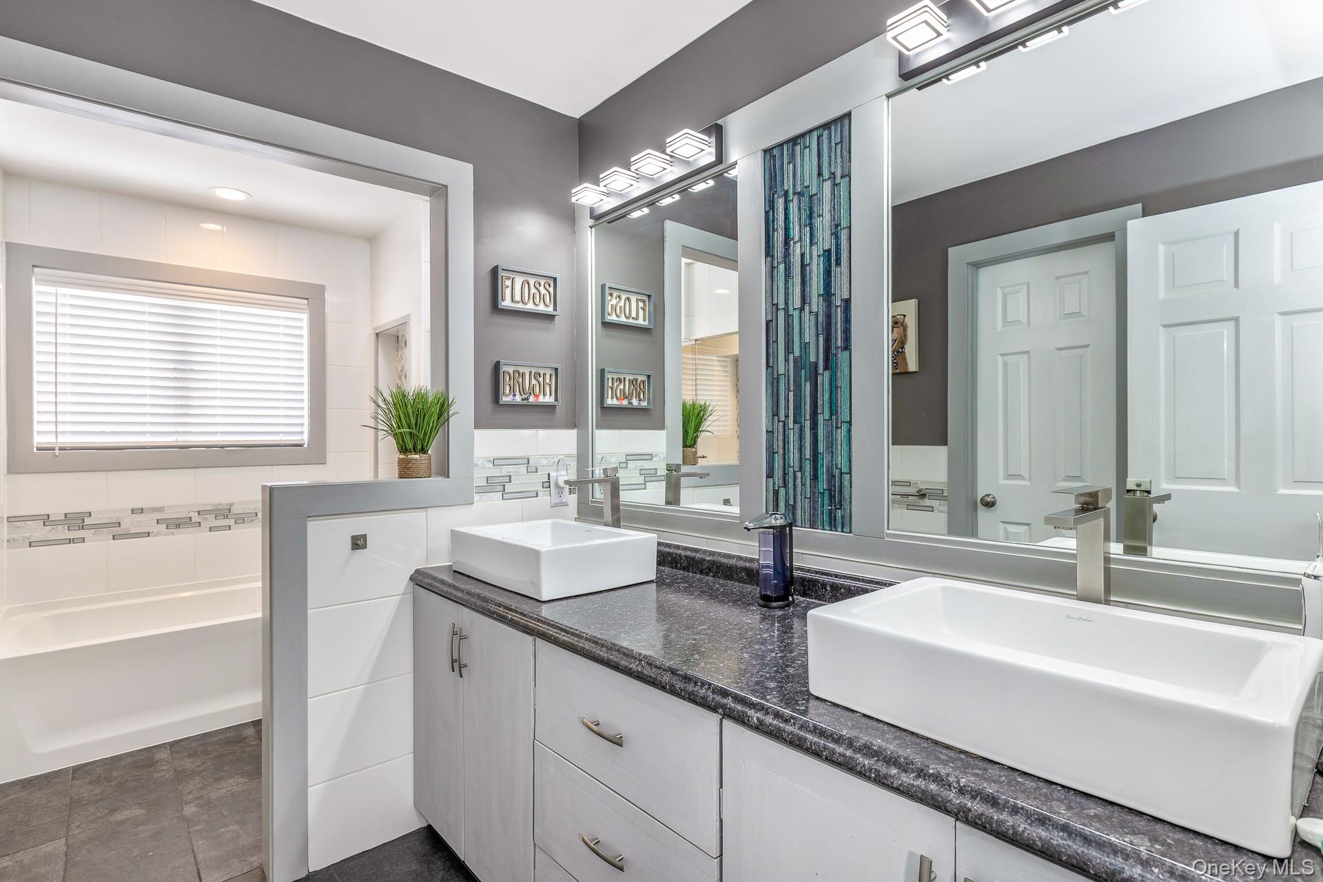503 Wading River Road Manorville, NY 11949 - Photo 27 of 45 Full bathroom featuring double vanity, tile walls, and a garden tub