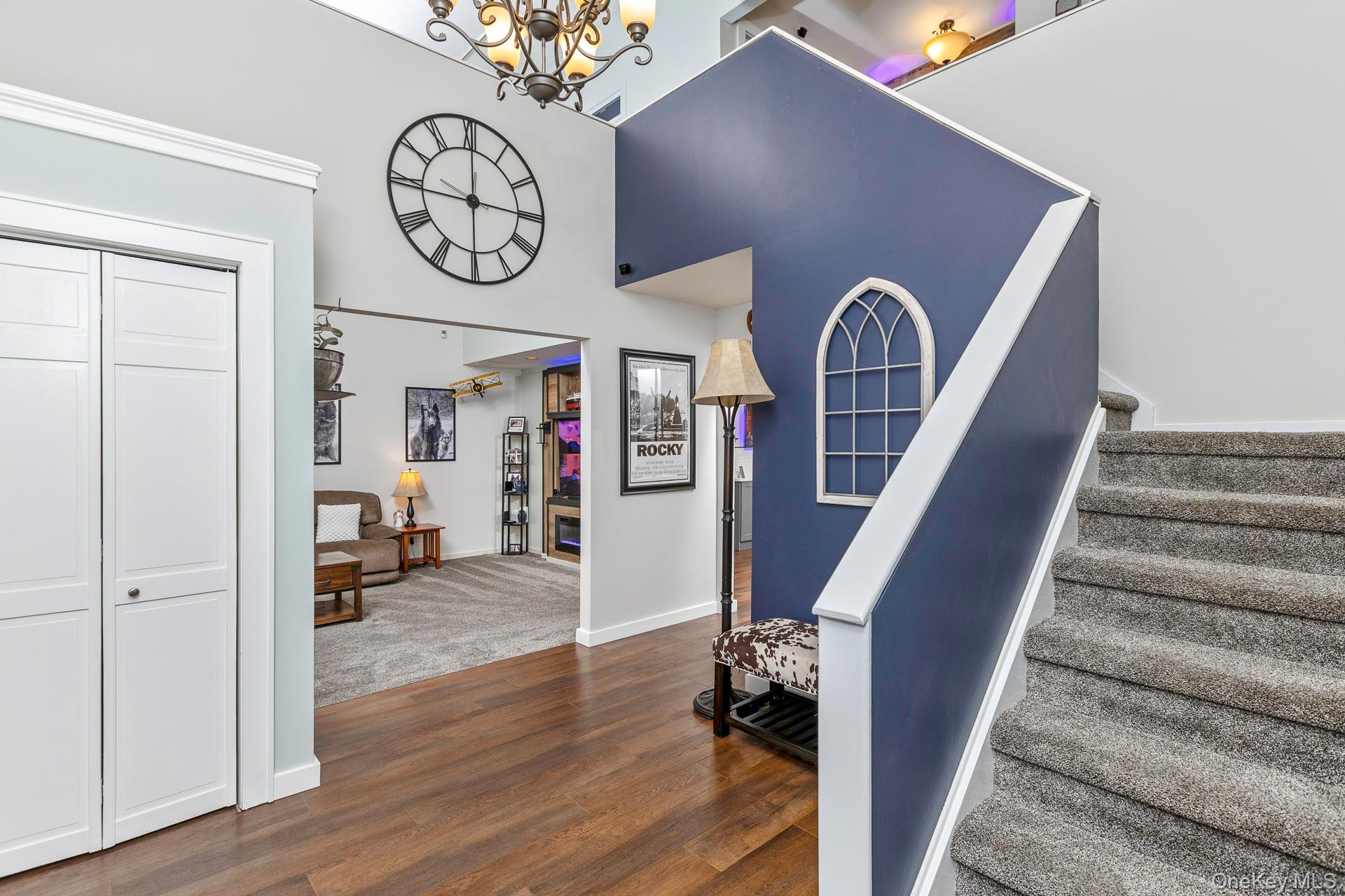 503 Wading River Road Manorville, NY 11949 - Photo 3 of 45 Stairs featuring wood finished floors, a high ceiling, and a chandelier