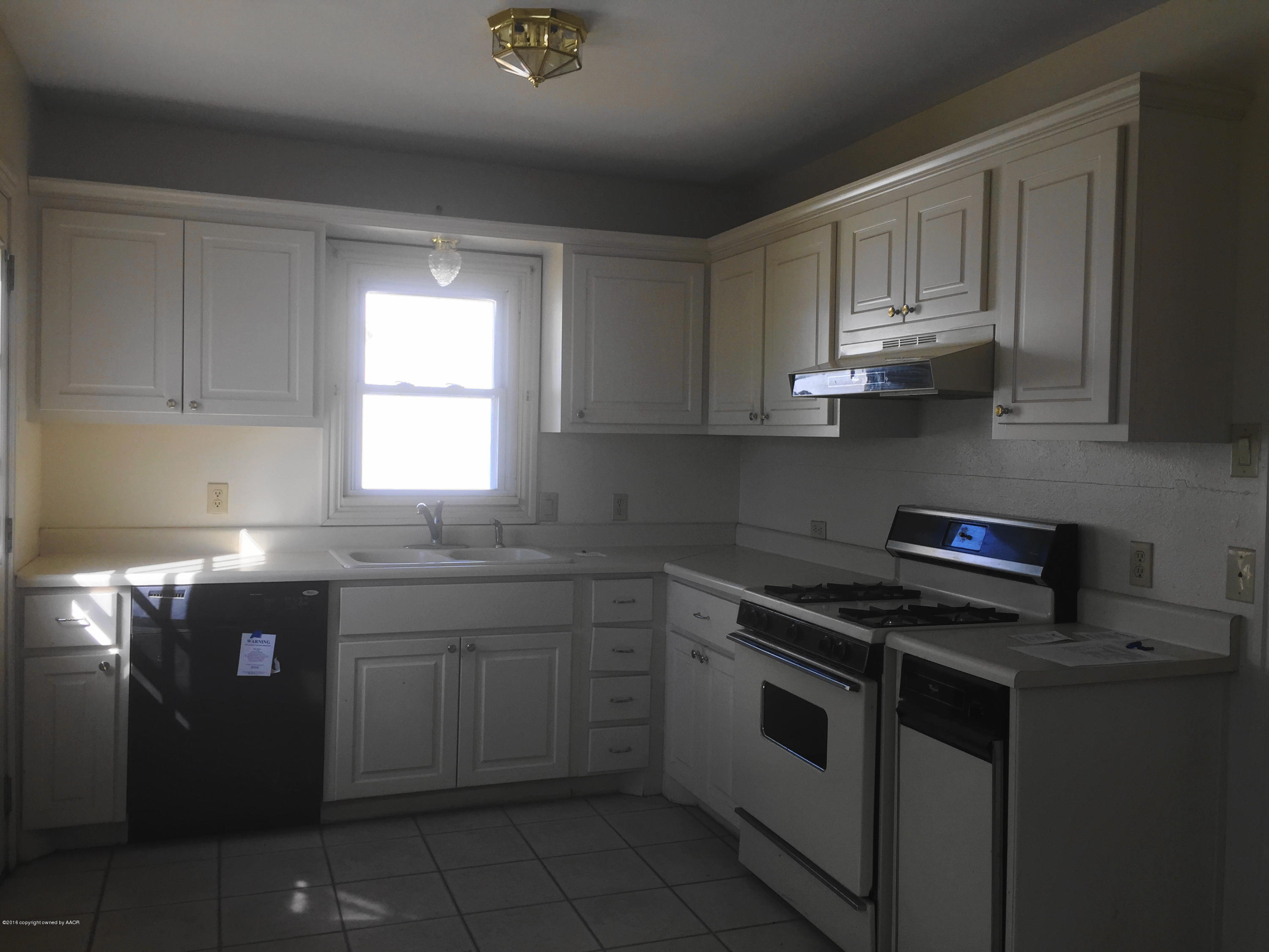 906 South Austin Street Amarillo, TX 79102 - Photo 3 of 10 a kitchen with granite countertop white cabinets and white appliances