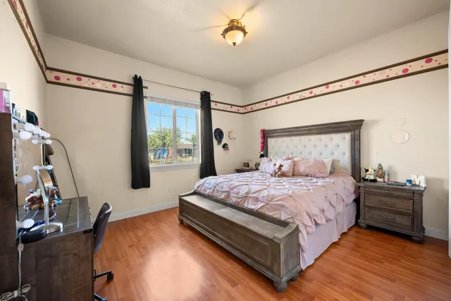 a bedroom with a bed window and a flat tv screen on the dresser