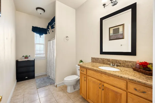 a bathroom with a granite countertop sink toilet and mirror