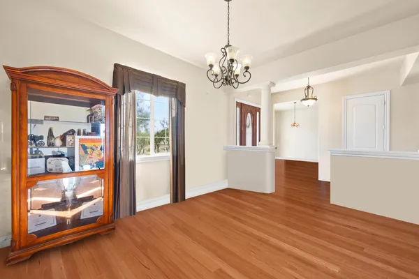 a dining room with wooden floor a chandelier a wooden table and chairs