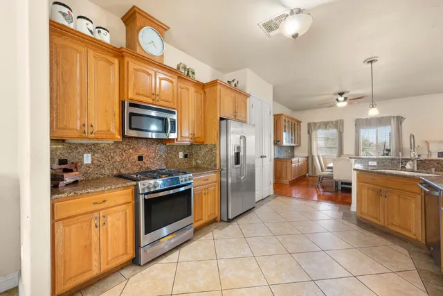 a kitchen with stainless steel appliances granite countertop a stove top oven a sink dishwasher and a refrigerator with wooden floor