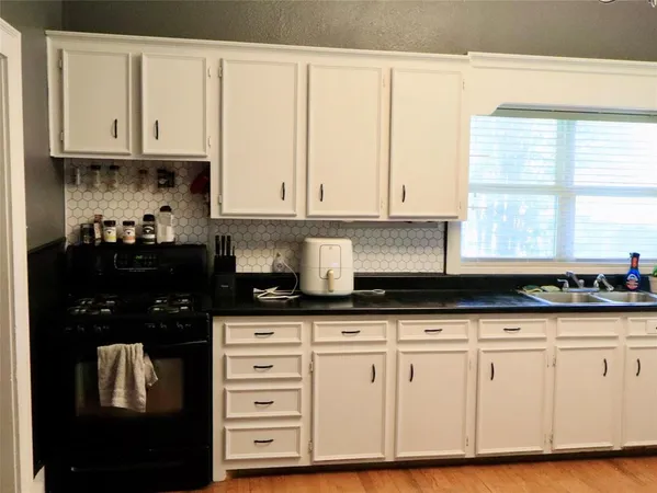 a kitchen with granite countertop white cabinets and black appliances