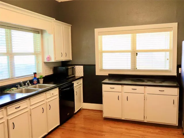 a kitchen with granite countertop a stove a sink and white cabinets with wooden floor