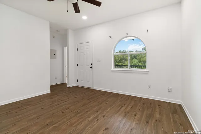 an empty room with wooden floor cabinet and windows