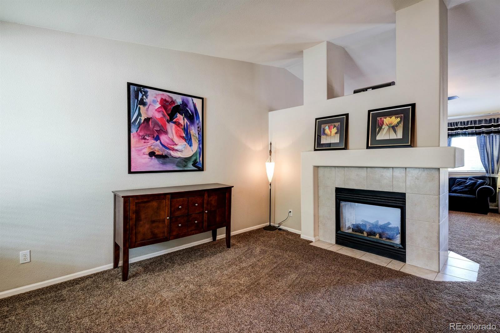 1045 Riddlewood Lane Highlands Ranch, CO 80129 - Photo 13 of 26 a living room with furniture a fireplace and a wall painting