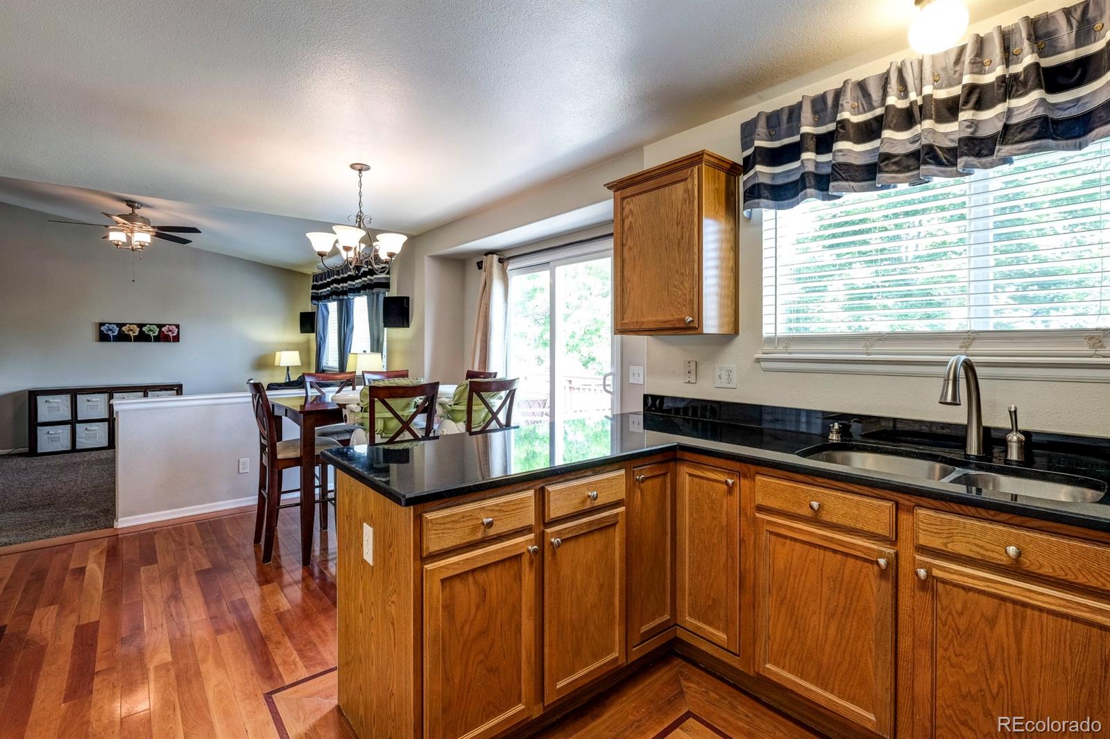 1045 Riddlewood Lane Highlands Ranch, CO 80129 - Photo 4 of 26 a kitchen with granite countertop cabinets a sink a dining table and chairs