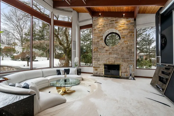 a living room with furniture a fireplace and floor to ceiling windows