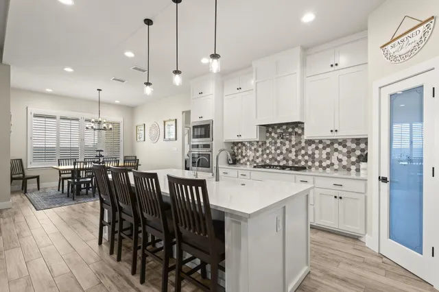a kitchen with stainless steel appliances kitchen island granite countertop a table chairs sink and cabinets