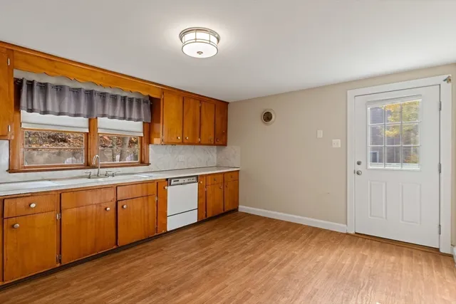 a view of a kitchen with a sink wooden cabinets and a window