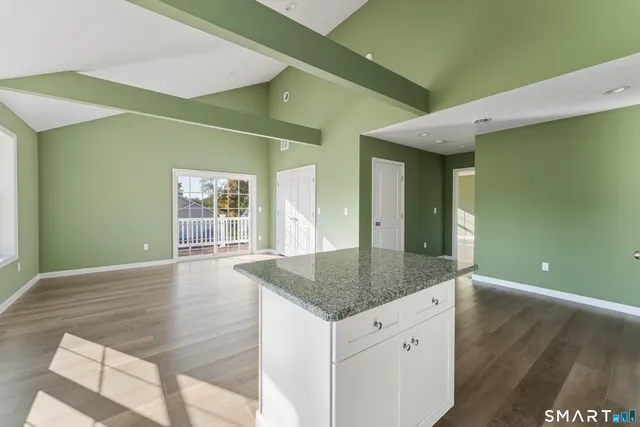 a kitchen with stainless steel appliances granite countertop a refrigerator a stove a sink dishwasher a dining table and chairs with wooden floor