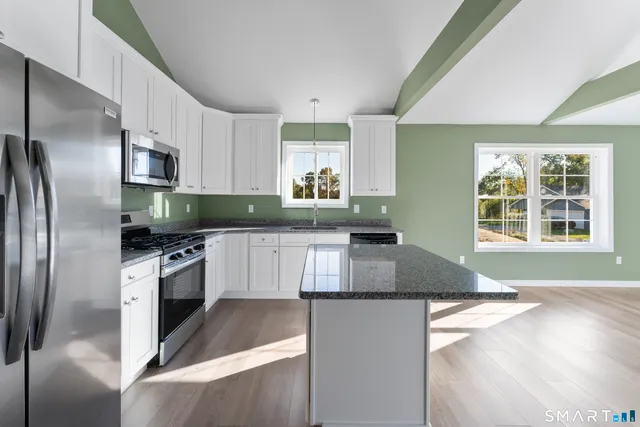 a kitchen with granite countertop a refrigerator a sink a stove a microwave a counter top space and cabinets