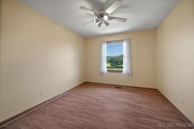 an empty room with a window and a ceiling fan