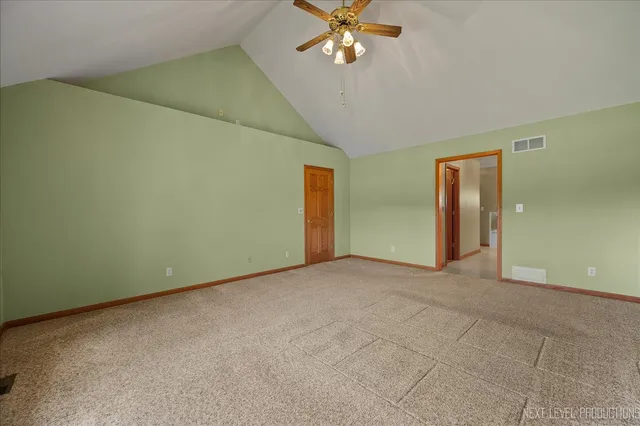 an empty room with a chandelier fan and windows