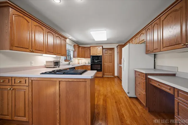 a kitchen with stainless steel appliances granite countertop wooden cabinets a refrigerator a sink and a stove