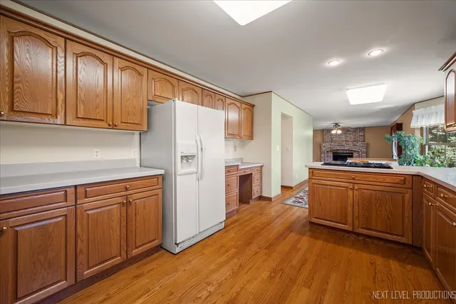 a kitchen with stainless steel appliances granite countertop a refrigerator a sink dishwasher and wooden cabinets with wooden floor