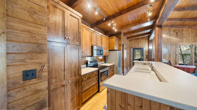 a kitchen with stainless steel appliances kitchen island granite countertop a refrigerator a stove and a wooden cabinets