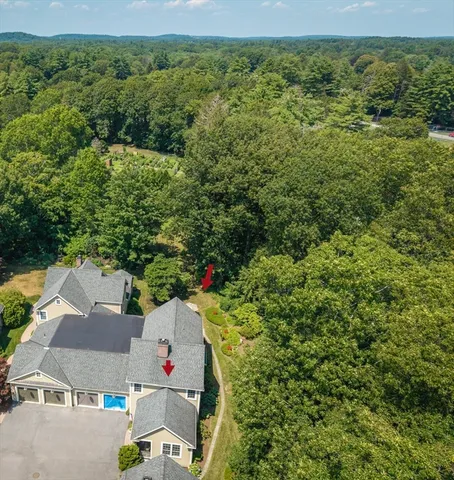 an aerial view of residential house with outdoor space and trees all around