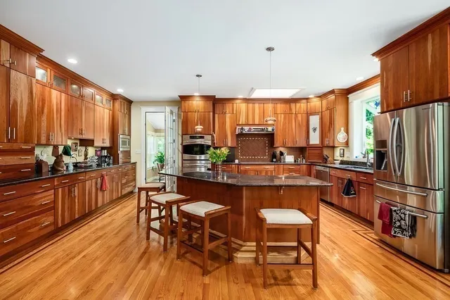 a kitchen with stainless steel appliances a table chairs refrigerator and cabinets