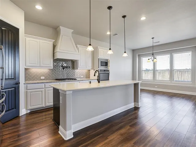 a kitchen with kitchen island a counter top a sink appliances and cabinets