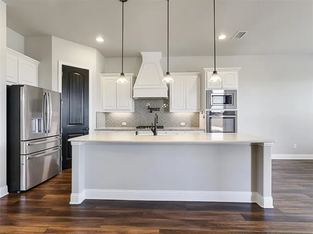 a kitchen with kitchen island a counter and a refrigerator