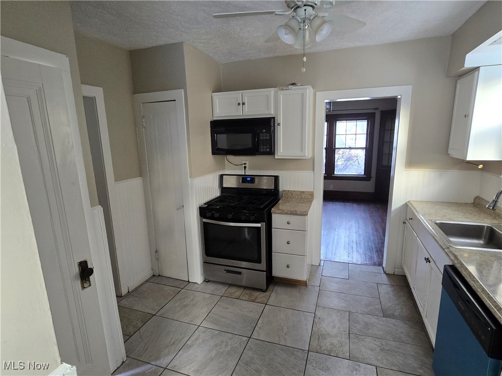 2048 Rossmoor Road Cleveland Heights, OH 44118 - Photo 10 of 29 Kitchen featuring white cabinets, gas stove, wainscoting, black microwave, and light countertops