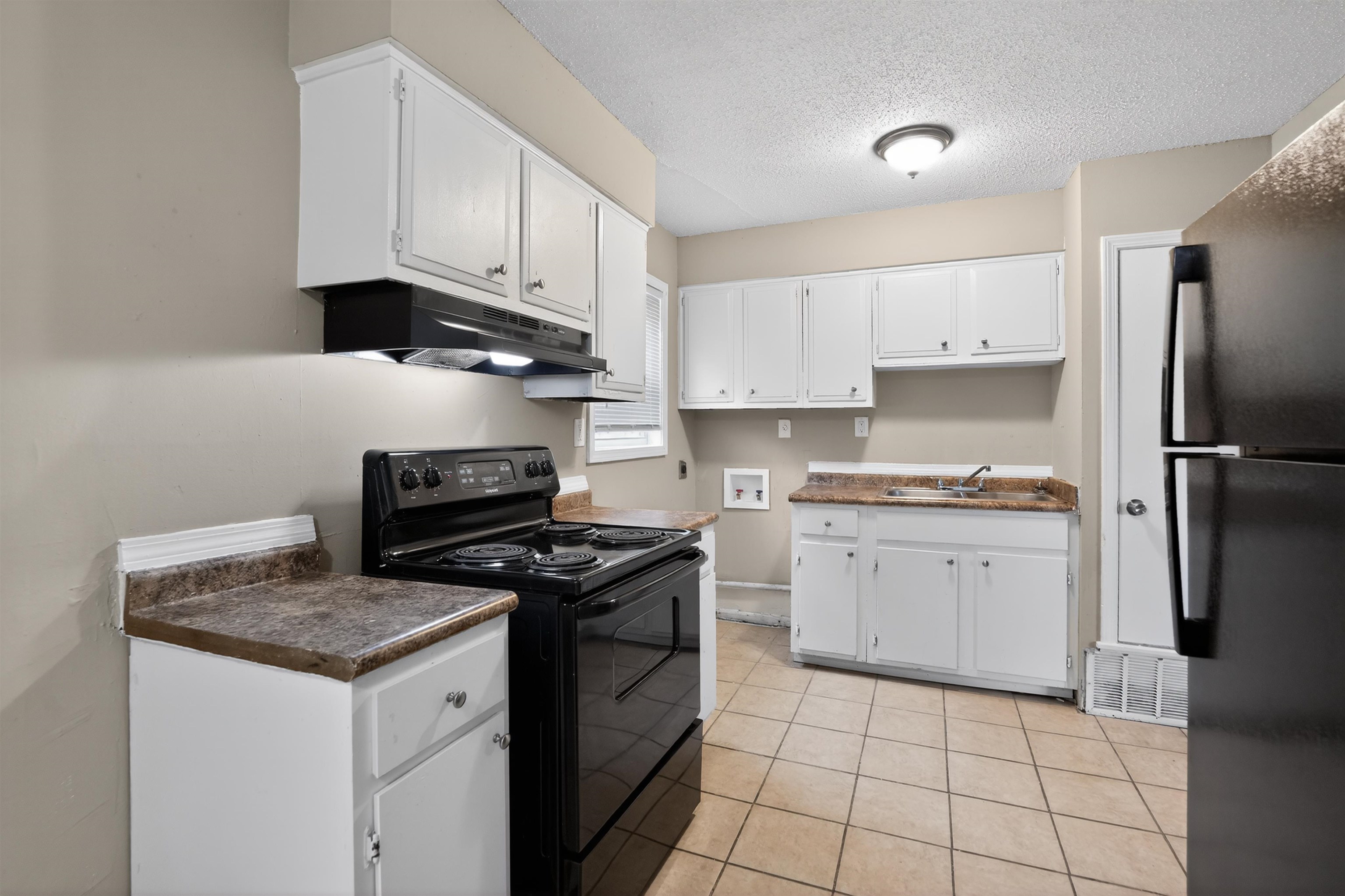 3608 Cane Ridge Drive Memphis, TN 38109 - Photo 20 of 31 Kitchen featuring white cabinetry, dark countertops, tile flooring, a black range, and a black refrigerator