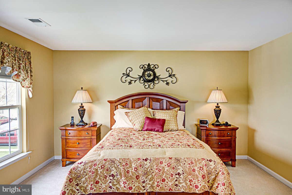 605 Sand Road Severn, MD 21144 - Photo 12 of 30 a bedroom with a bed and a lamp on dresser