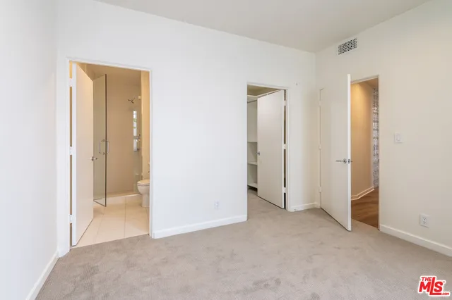 a view of an empty room with closet and a bathroom