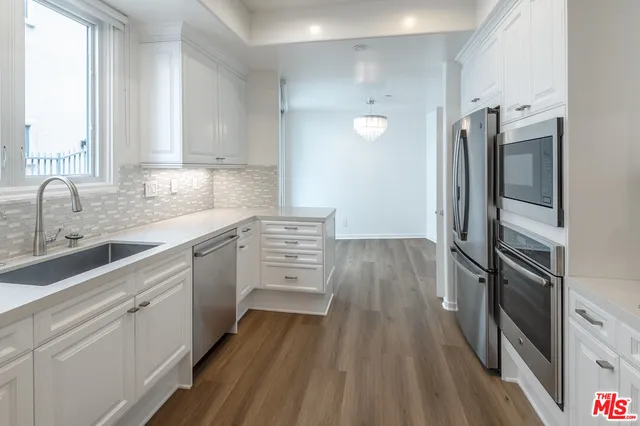 a kitchen with a sink appliances wooden floor and cabinets