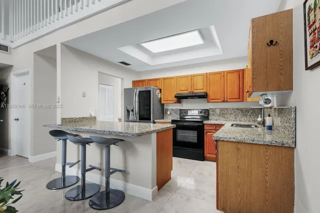 a kitchen with stainless steel appliances granite countertop a stove a sink and a refrigerator