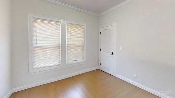 a view of an empty room with window and wooden floor