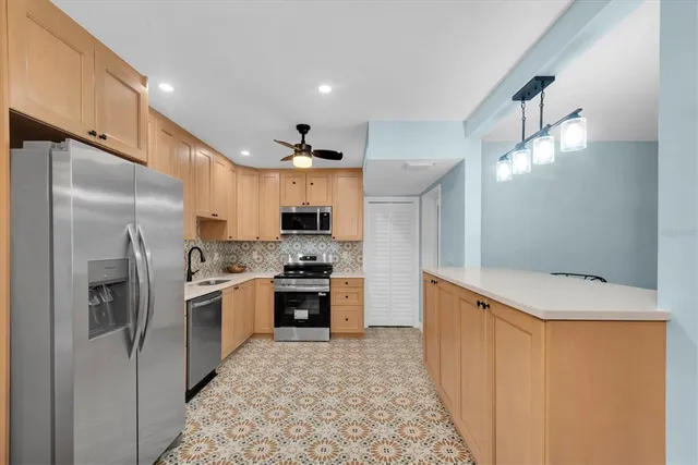 a kitchen with stainless steel appliances granite countertop a refrigerator a stove and a sink